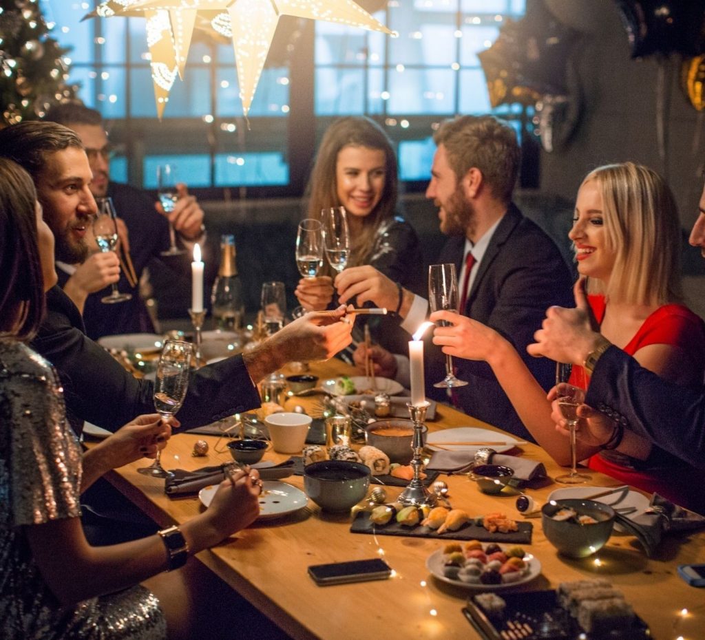 Elegantly dressed group toasting with champagne glasses at a festive Christmas party dining table.